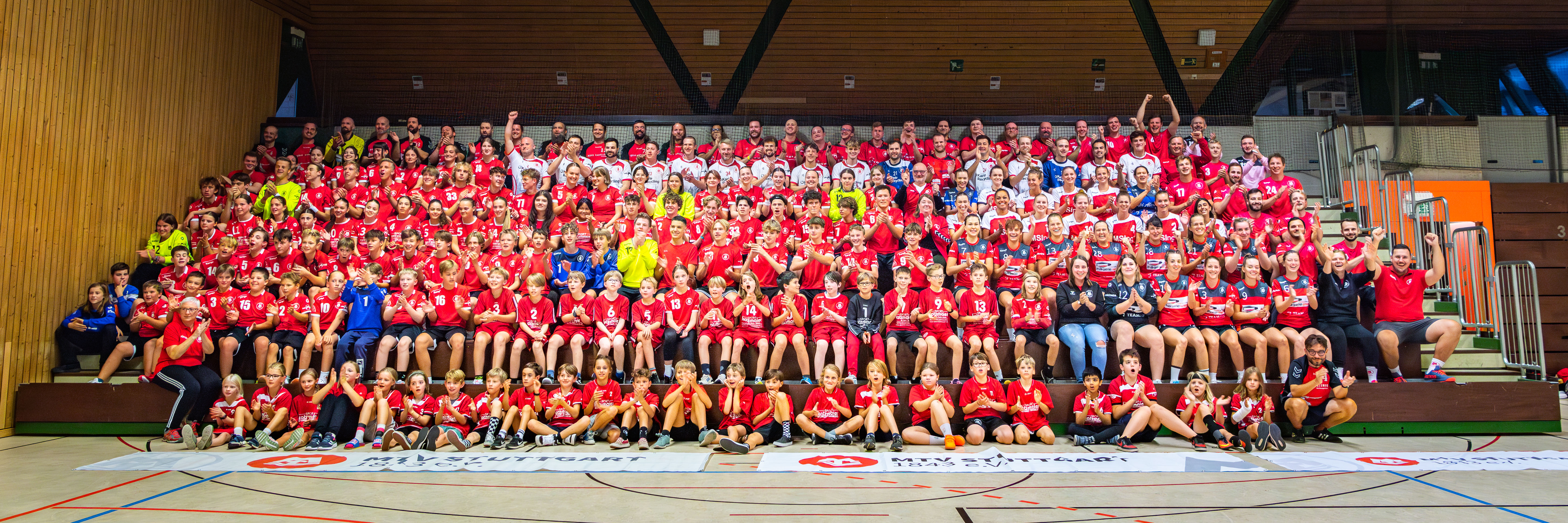 Das Bild zeigt alle 300 Handballerinnen und Handballer auf der Tribüne sitzend