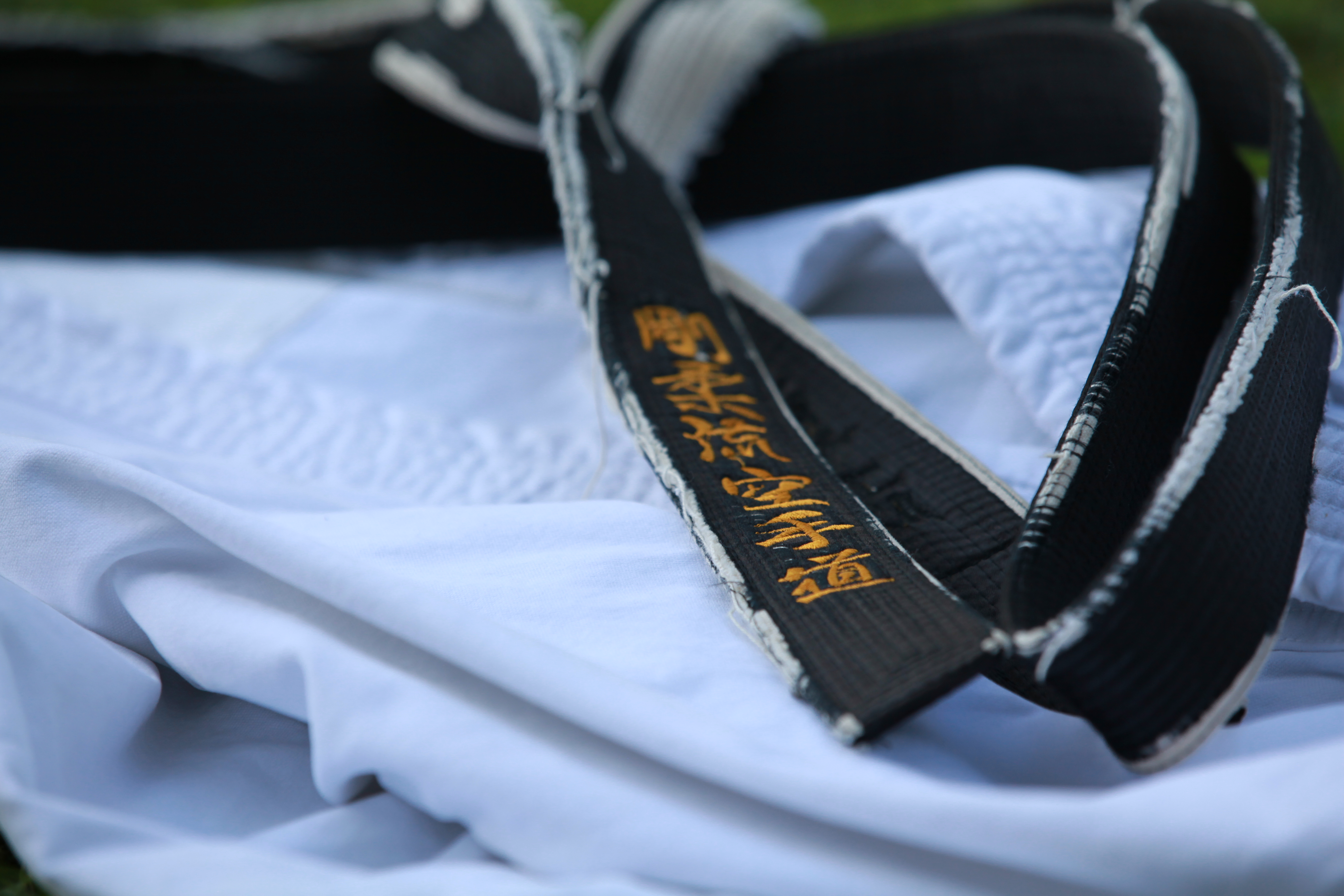 Auf dem Bild ist der schwarze Gürtel auf einem weißen Karate-Anzug in Nahaufnahme zu sehen.
